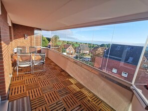 Un balcon avec un plancher en bois, une table et deux chaises.