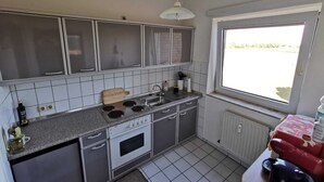 Cuina compacta amb fogó a gas, forn i finestra que deixa entrar llum natural.