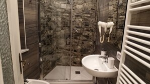 Un baño moderno con ducha de vidrio, lavamanos pedestal y bidé.