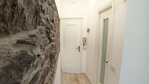 Un pasillo con una pared texturizada en un lado y una puerta al final.