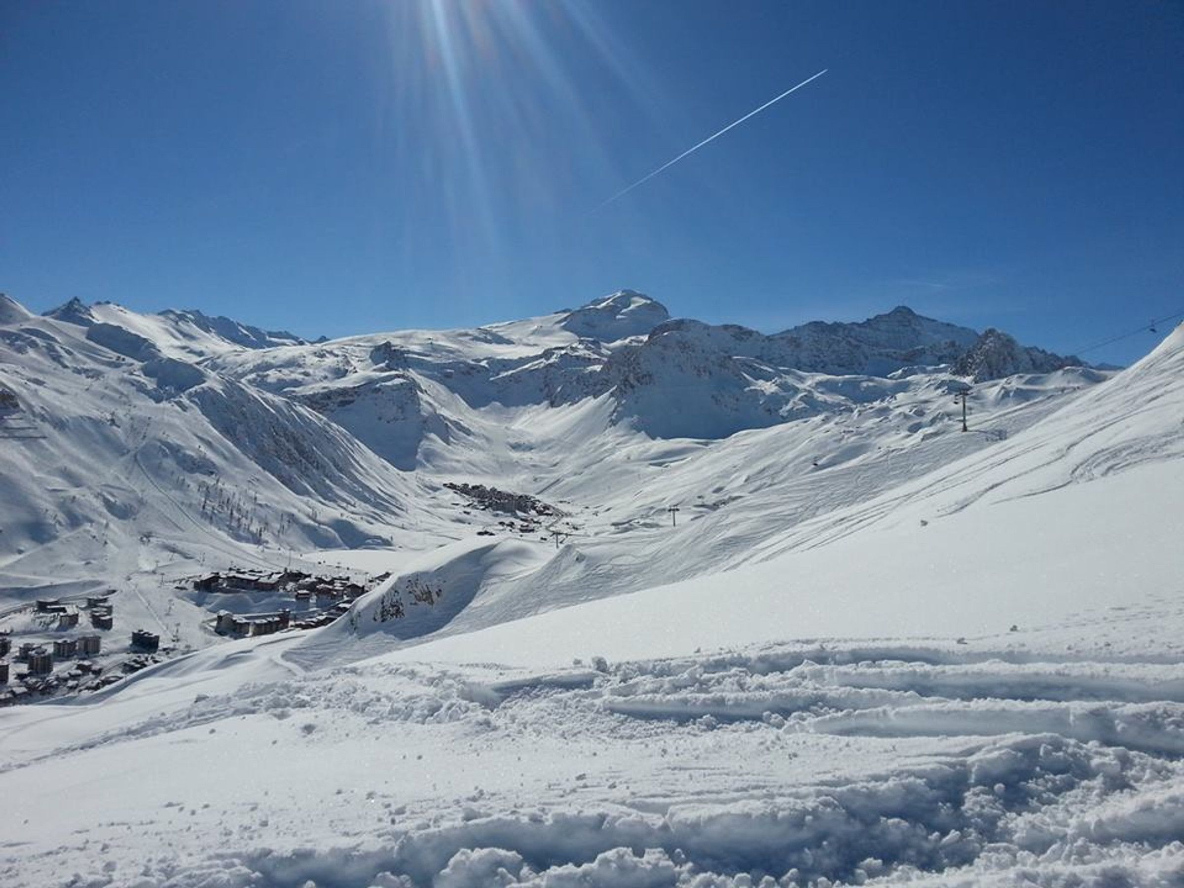 A snow-covered mountain landscape with a small settlement and ski lift.
