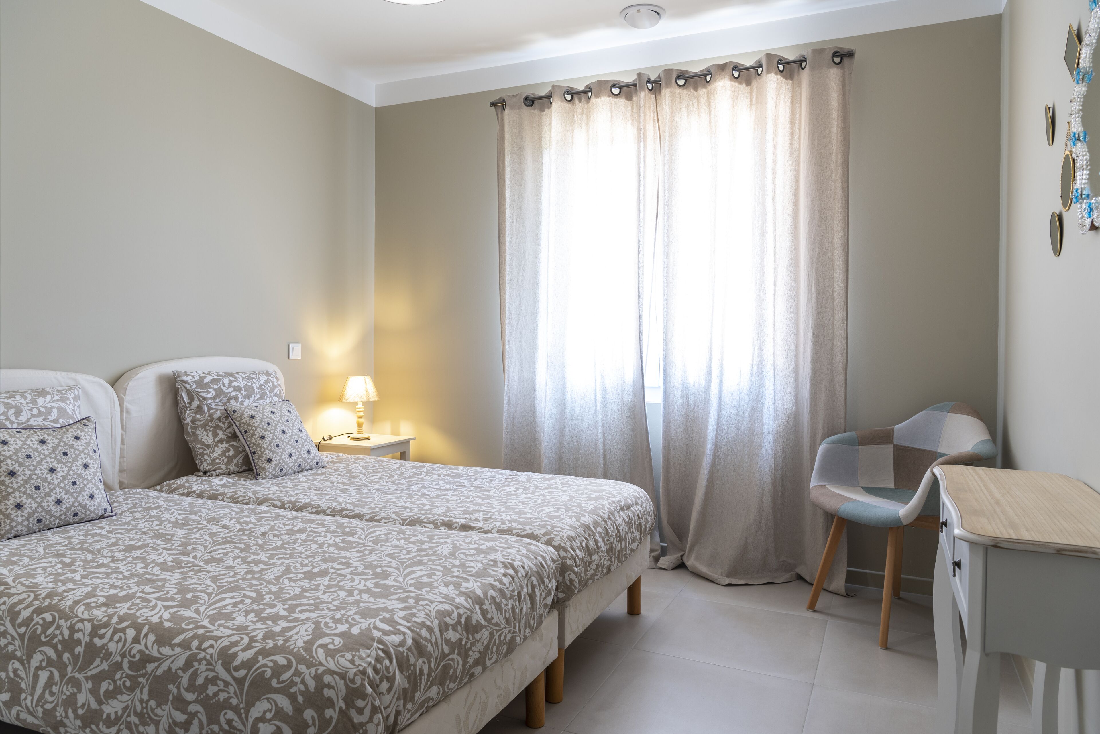 A bedroom with two beds, a desk, and a chair.