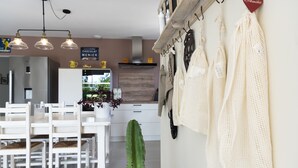 Una cocina moderna con armarios blancos, una zona de comedor con sillas blancas y una toalla de cocina colgando.