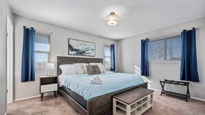 Ein Schlafzimmer mit Bett, Nachttischen, einer Bank und einer Deckenleuchte.