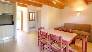 A spacious living area with a wooden ceiling, a dining table with chairs, a sofa, and a kitchen area with cabinets and a countertop. - Garden-Level Apartment, 3 Rooms, 6 Guests, Near Liscia Beach (Calcatoggio)