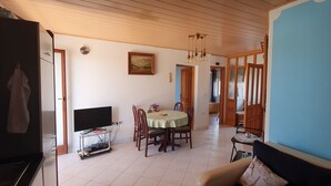A dining area with a table, chairs, and a television on a stand. - Nice, quiet, and inexpensive family apartment with proximity to sandy beach (Privlaka)