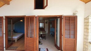 A room with a bed, a desk, and a chair. There is a window with wooden shutters. - Nice, quiet, and inexpensive family apartment with proximity to sandy beach (Privlaka)
