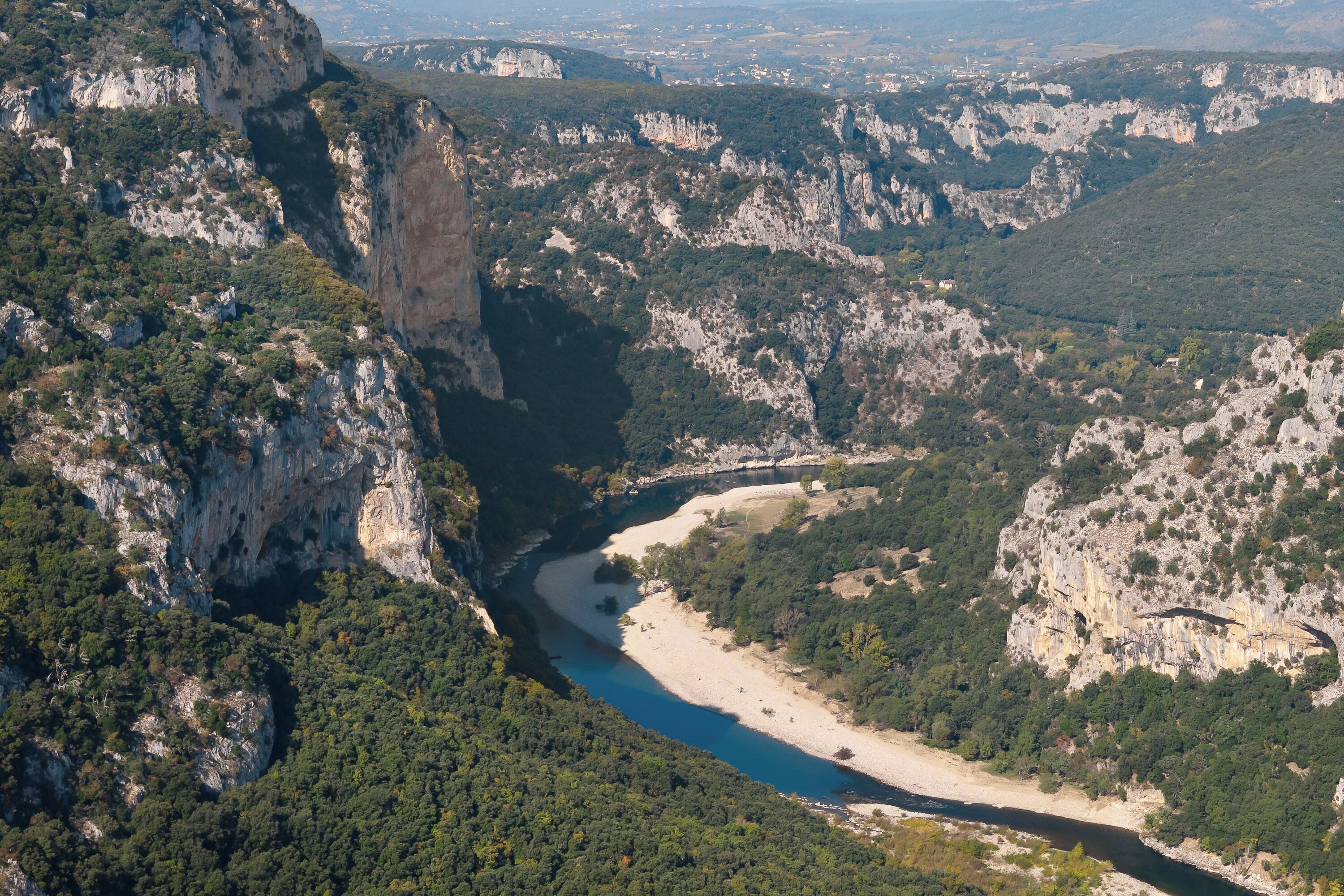A canyon with a river, cliffs, and sparse vegetation.