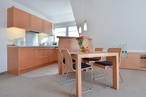Una cocina moderna con armarios de madera, una mesa de comedor con sillas y un microondas.