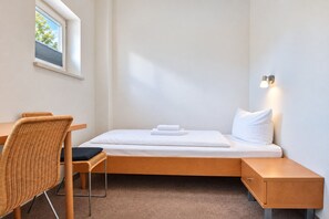 Ein kleines Schlafzimmer mit einem Einzelbett, einem Schreibtisch und einem Stuhl.