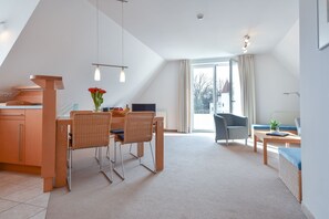 En moderne stue med spiseplads, med et stort vindue, en sofa og et sofabord.