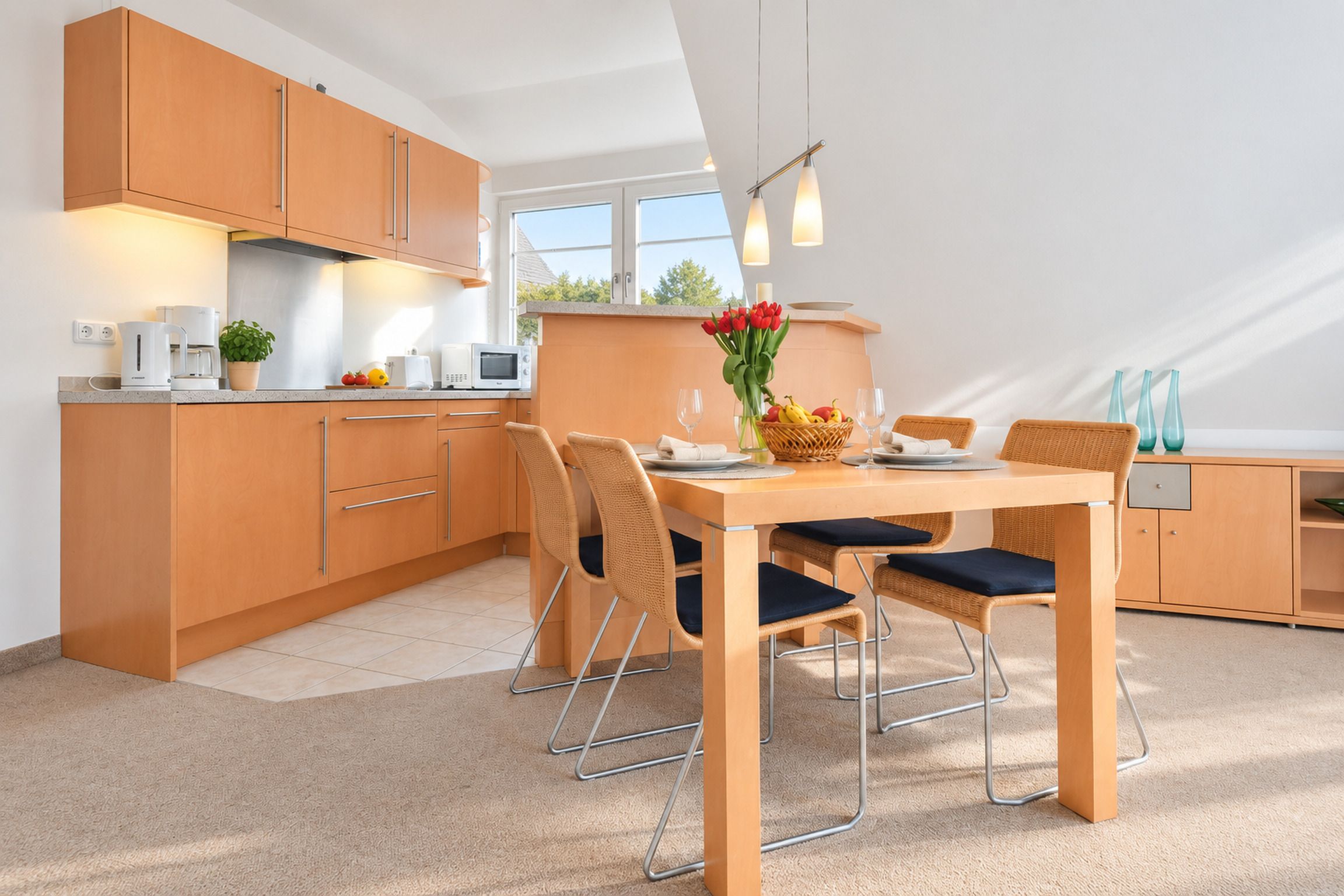 Een moderne keuken met houten kasten, een eettafel met stoelen en uitzicht op de omgeving via een raam.
