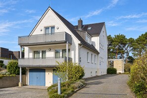 Ein zweistöckiges Haus mit Balkon, Garage und gepflasterter Auffahrt.