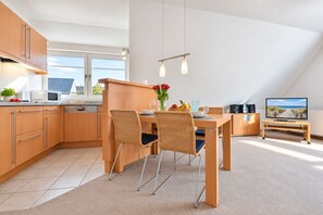 Eine moderne Küche mit Essbereich, Fernseher und Balkon.