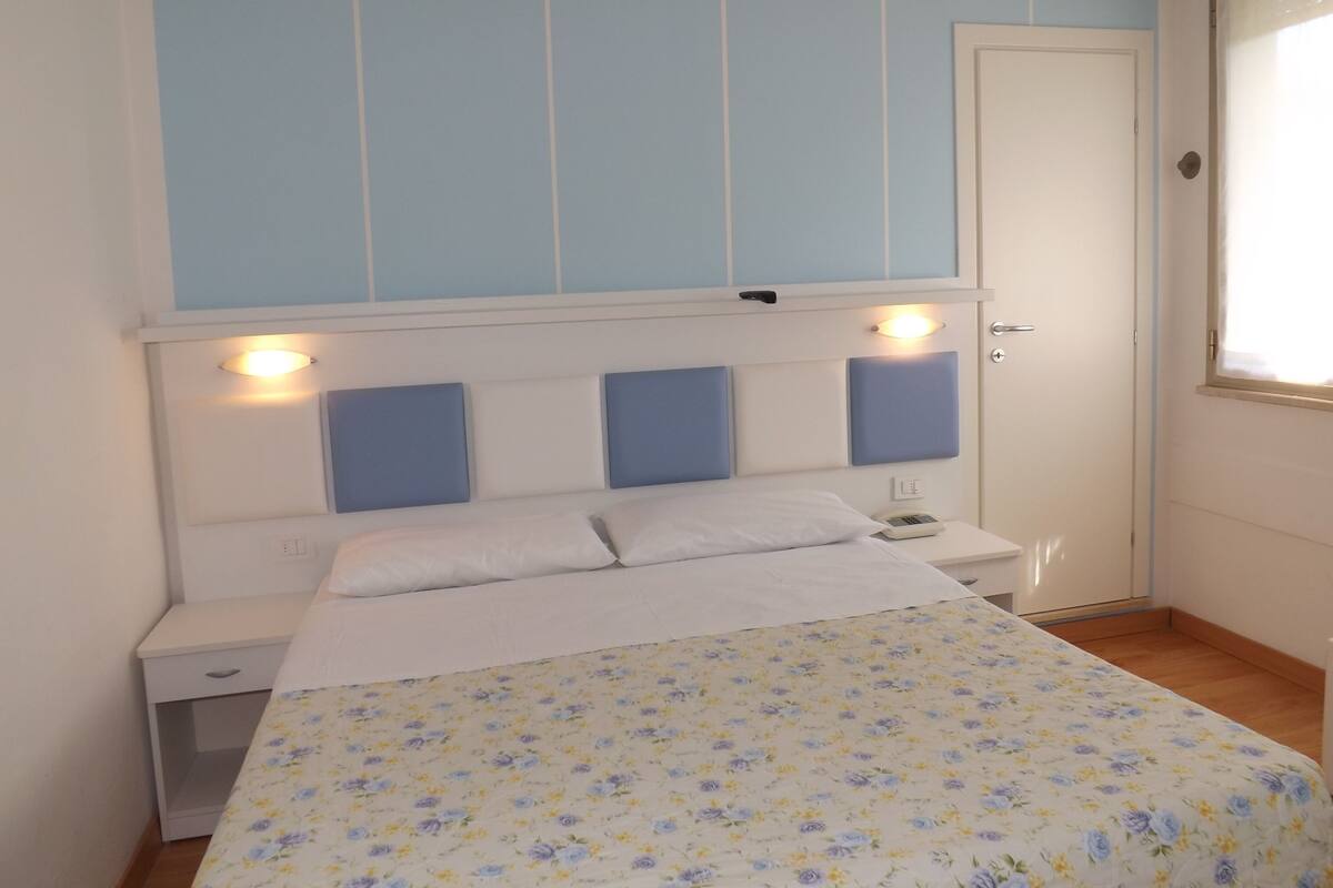 Une chambre à coucher avec un lit, des tables de chevet et une porte.