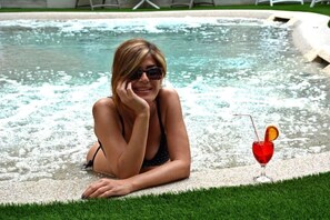 Une personne dans une piscine, avec une boisson à portée de main.