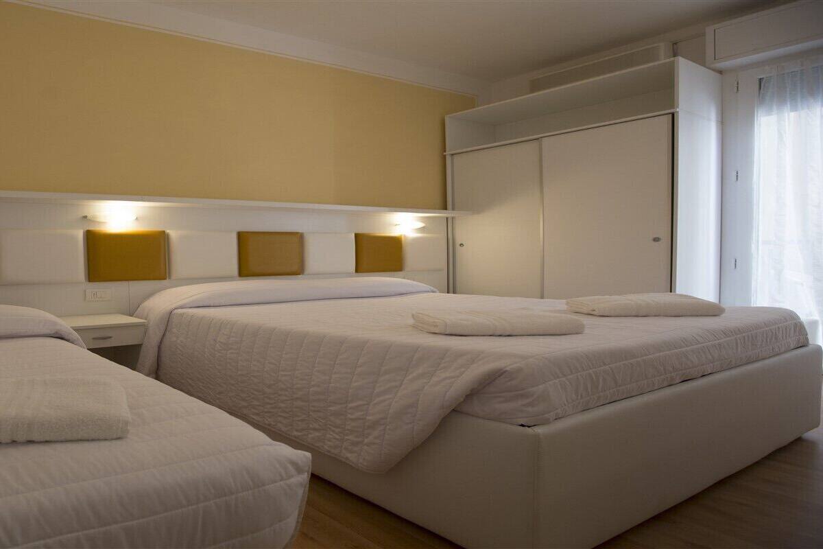 Une chambre d’hôtel avec deux lits simples, une armoire et une table de chevet avec une lampe.