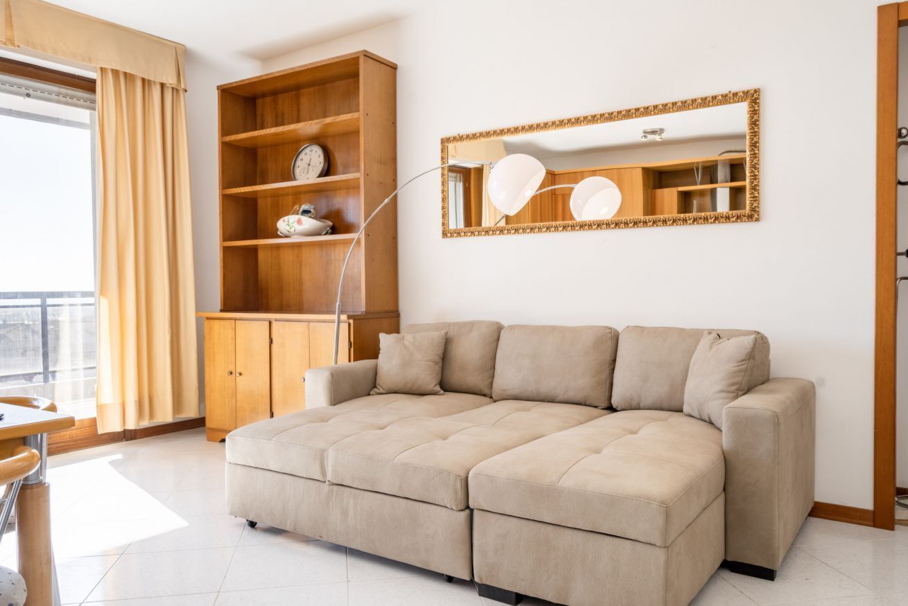 Un salon avec un canapé beige, des étagères en bois, une horloge et un miroir décoré de ballons.