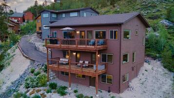 A multi-story house with a balcony, surrounded by natural landscape.