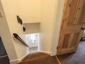 A staircase with carpeted steps leading to a landing with a window.