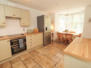 A compact kitchen with a built-in oven, a refrigerator, and a dining area with a table and chairs.