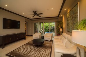 A modern living room with a flat-screen TV, a ceiling fan, a sofa, and a coffee table. - Vista Bahia 3D 3 bdr Ocean View in Los Suenos (Playa Herradura)