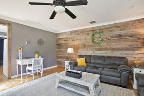 A living room with a grey sofa, a white desk, and a ceiling fan. - 🌻 Charming Cottage On Peaceful 5 Acres in the Mountains (Central Point)