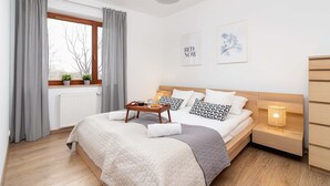 A neatly arranged bedroom with a bed, bedside table, and a window with curtains.