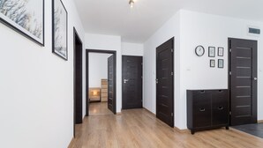A hallway with wooden flooring, dark doors, and framed pictures on the walls.