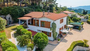A two-story house with a red-tiled roof, surrounded by lush greenery and a well-maintained garden. - Appartamento Villa da 2 Fino a 4 Persone Giardino (Capoliveri)