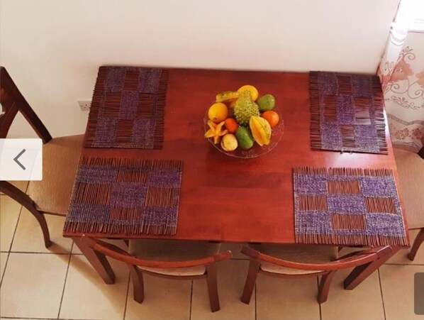 A wooden dining table with a woven placemat, surrounded by chairs.