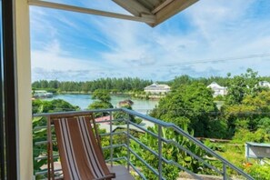 A balcony with a view of a river and greenery.