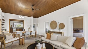 Un vaste salon doté d’un plafond en bois, d’une table basse ronde, d’un canapé beige et d’un coin repas avec des chaises et une table.