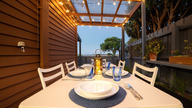Une table dressée pour quatre personnes, avec de l’argenterie blanche, de la verrerie bleue et un chandelier en guise de centre de table.