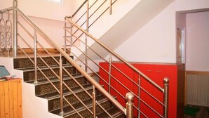 Una escalera con barandillas de metal ornamentadas y un armario rojo a la derecha.