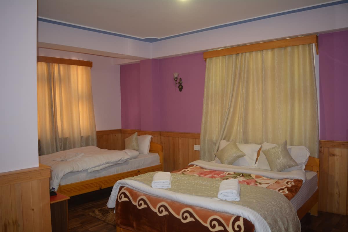 A hotel room with two beds, wooden headboards, and a large window with curtains.