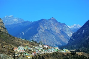 A mountainous village with colorful buildings nestled in a valley. - Rufina Lachung De'Crown (Chungthang)