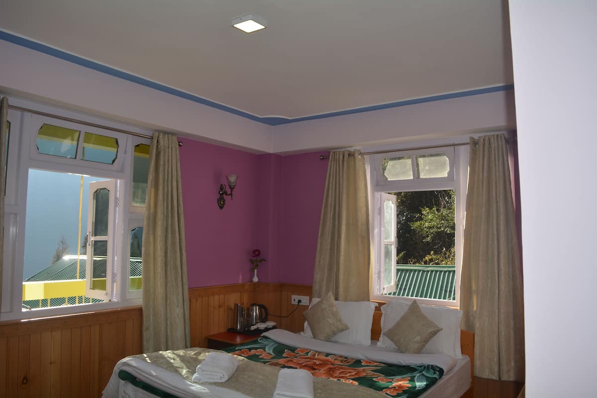 A bedroom with a bed, a nightstand, a lamp, and a window with curtains.