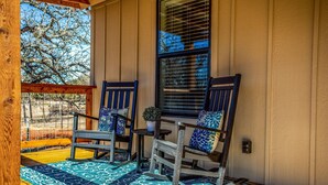 A porch with two rocking chairs, a small table, and a potted plant.