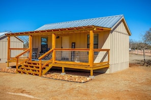 A small guest house with a covered porch and wooden staircase.