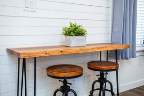 A stylish bar stool sits on a white floor, complemented by a planter with a lush green plant.