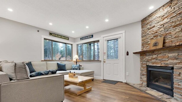 A living room with a stone fireplace, a sofa, a coffee table, and a door labeled 'DREAM MAKER.'