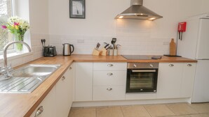 A modern kitchen with white cabinets, a stainless steel sink, a kettle, and a toaster. - Sea Change (Whitby)