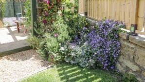 A garden with a wooden fence, a stone wall, and various plants and flowers. - Sea Change (Whitby)