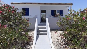 Un bâtiment moderne, de couleur blanche, avec des volets bleus, une entrée centrale et un étroit chemin menant à la porte.