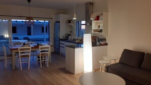 Une cuisine moderne avec un îlot central, un coin repas comprenant une table et des chaises, un canapé et une petite table basse.