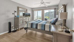 A bedroom with a bed, dresser, and a large window.