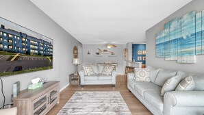 A modern living room with a grey sofa, a coffee table, and a TV mounted on the wall.