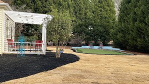 A covered patio area with outdoor furniture and a small tree.
