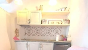 A small, cozy room with a bed, a kitchenette, and a wooden ceiling.
